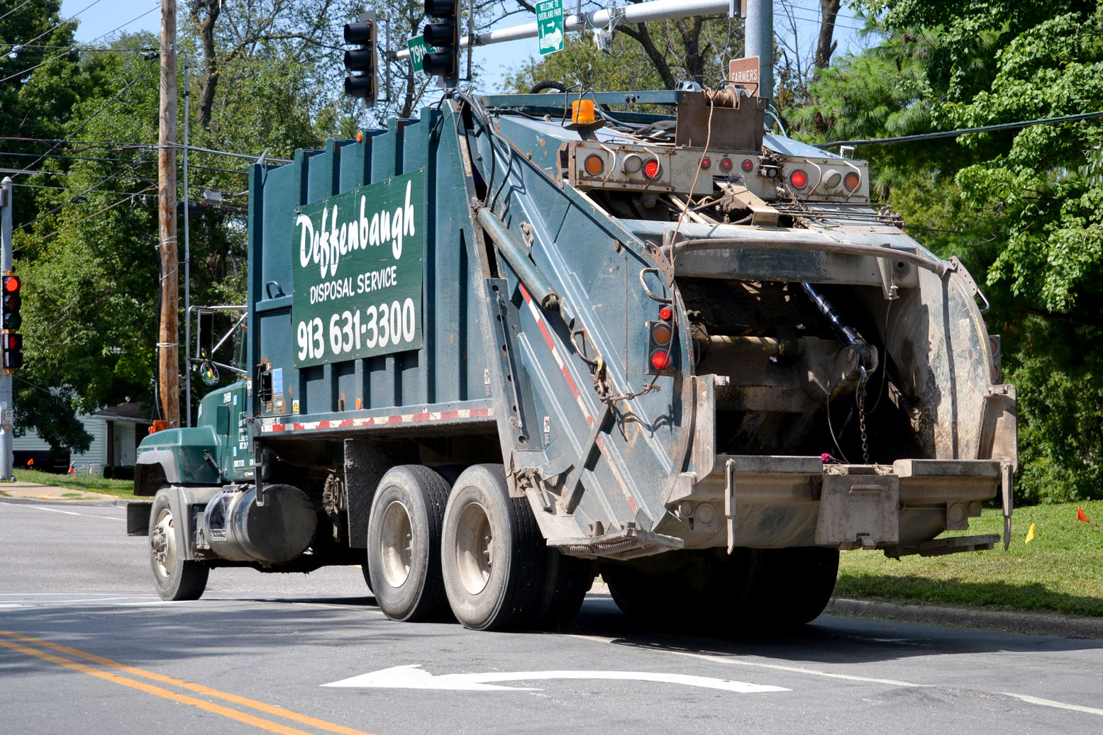 Green Deffenbaugh trash truck waits at a red light
