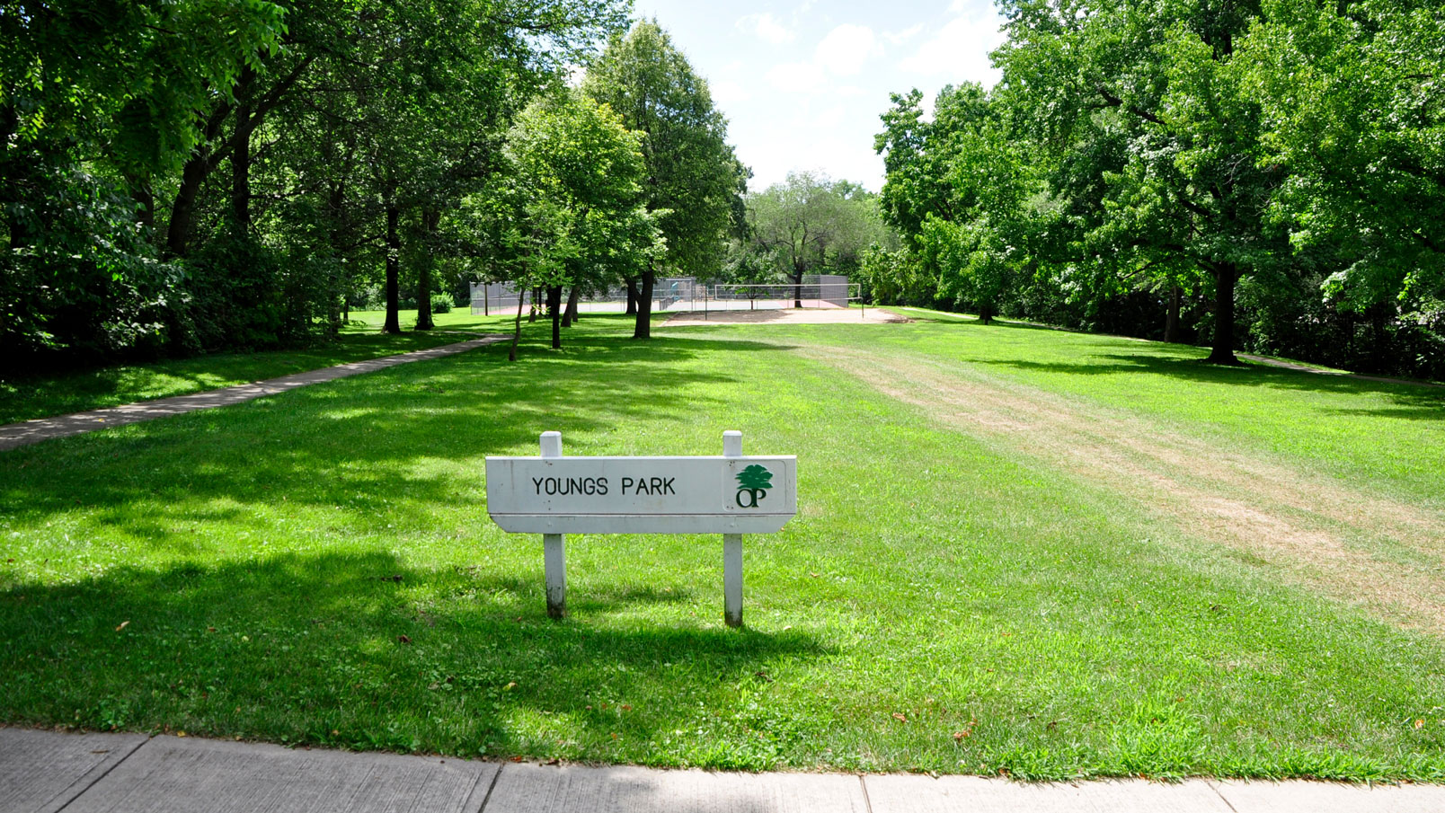 Green open space bordered by trees and Young's Park entrance sign