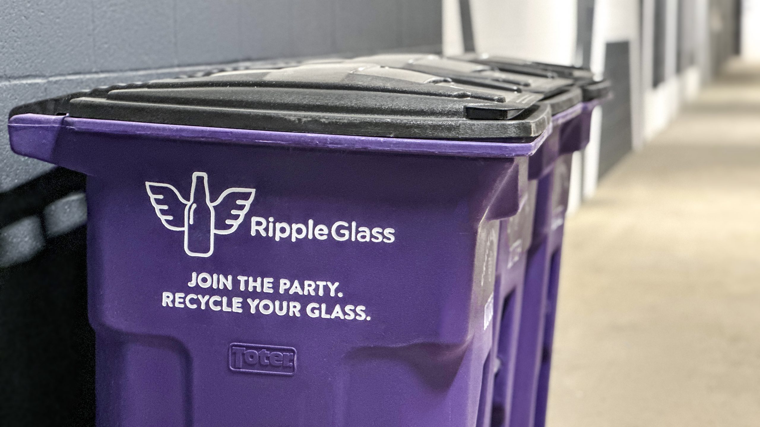 Purple Ripple Glass recycling bins are placed in an apartment parking garage