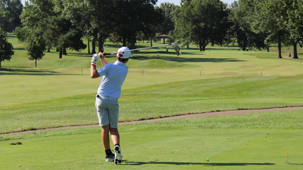 A young golfer completes a practice swing at a youth golf tournament.