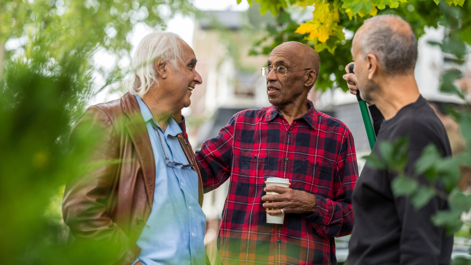 Three neighbors chat in a driveway.