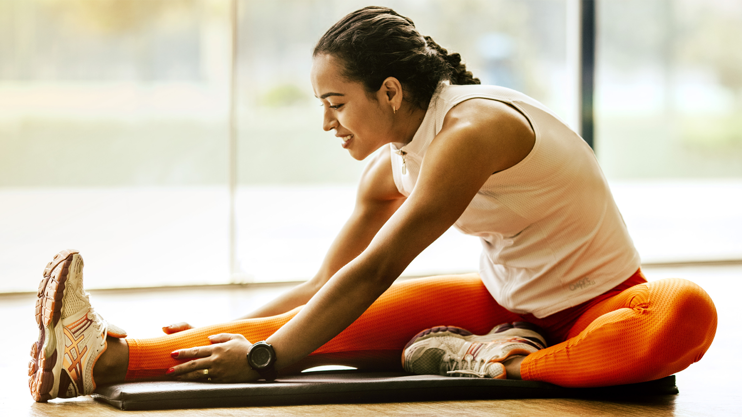 A women stretches her legs on a workout mat.