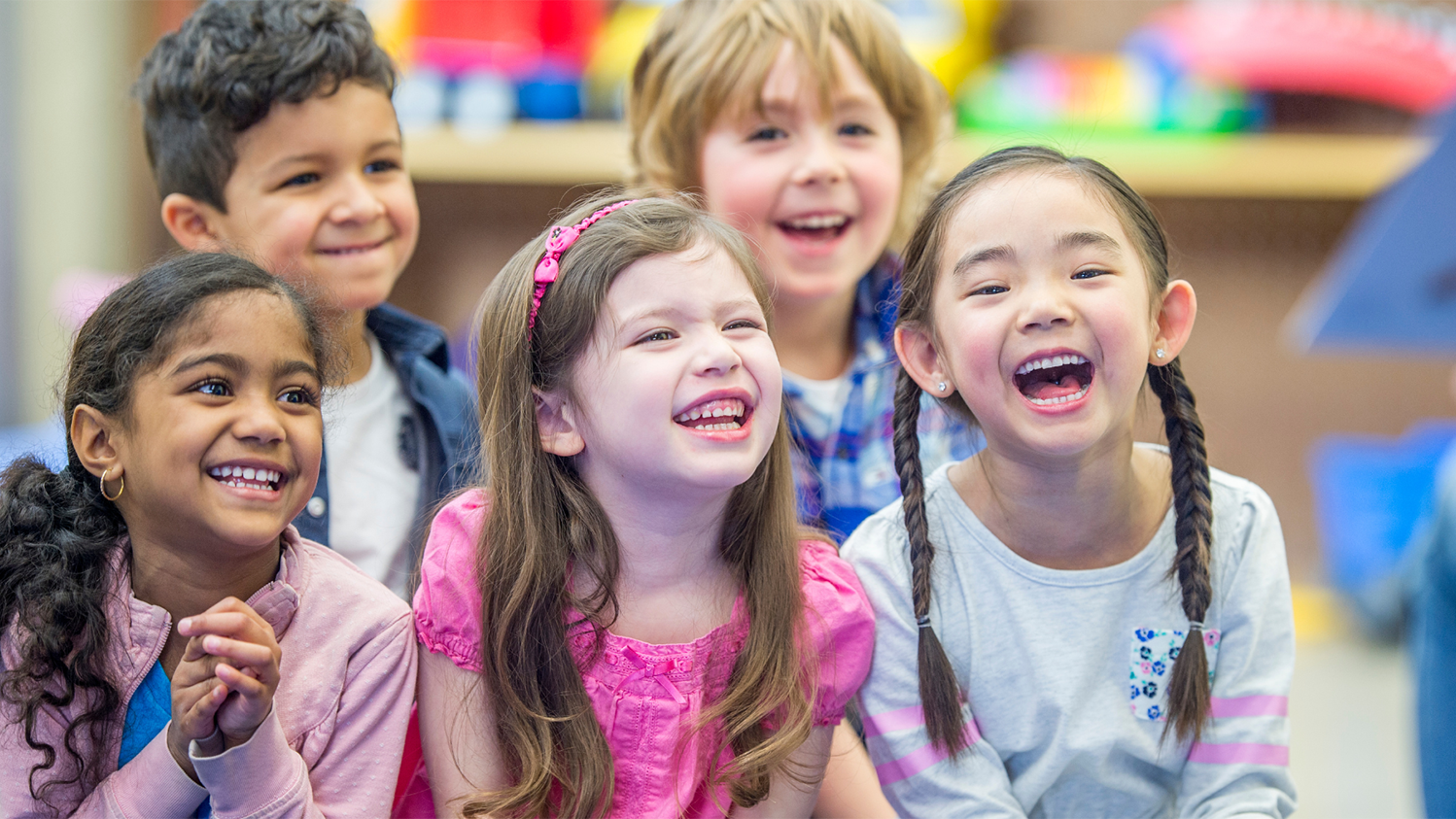 A group of young children smile and laugh.