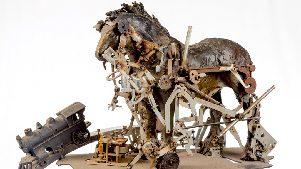 An art piece features a bronze horse statue with various construction pieces attached to the outside of its body.