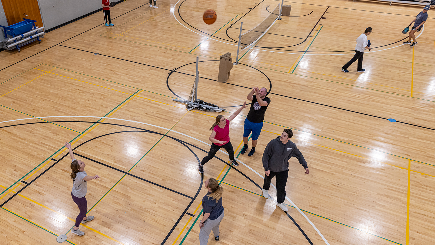 A small group of people plays basketball in the gymnasium at Matt Ross Community Center.
