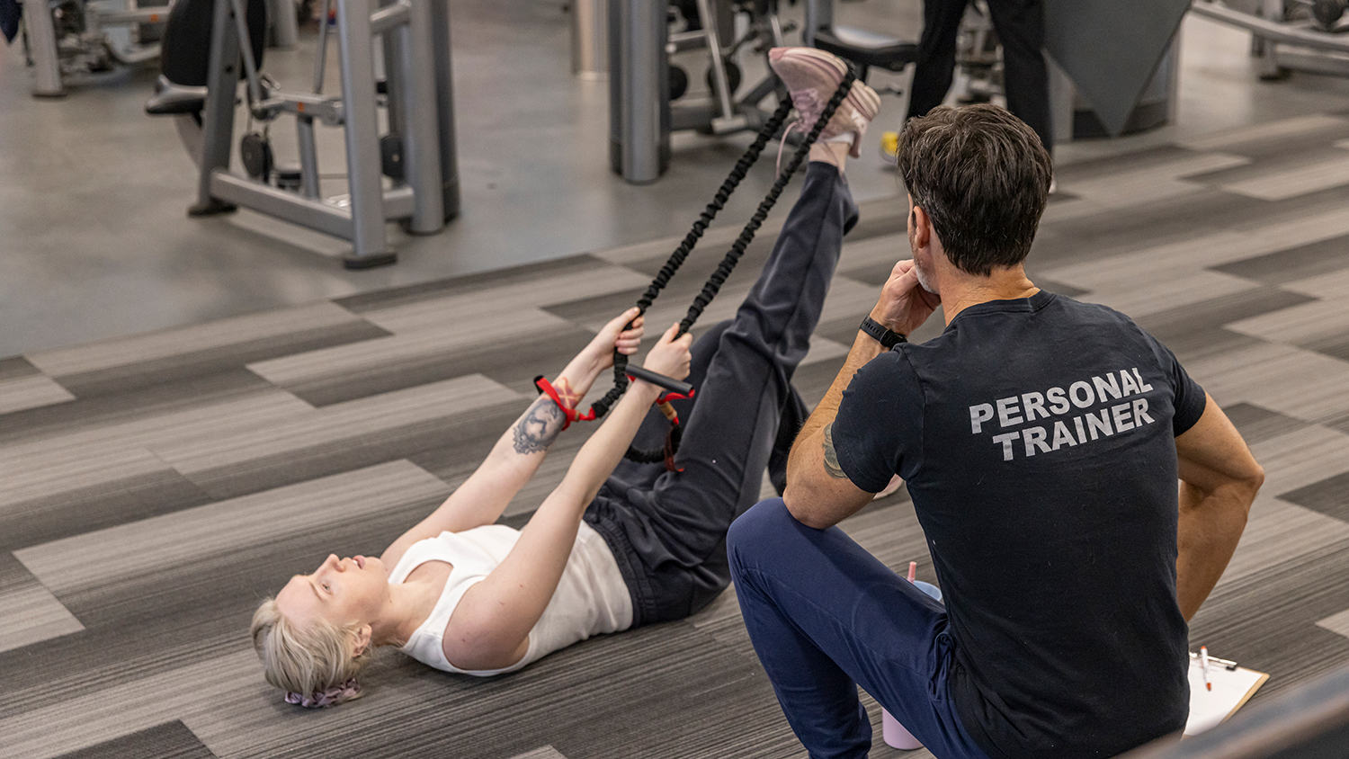 A personal trainer helps a client stretch.