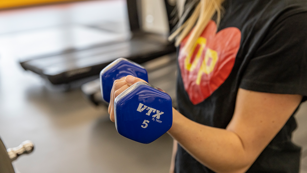 A close-up of an arm lifting a five-pound dumbbell.