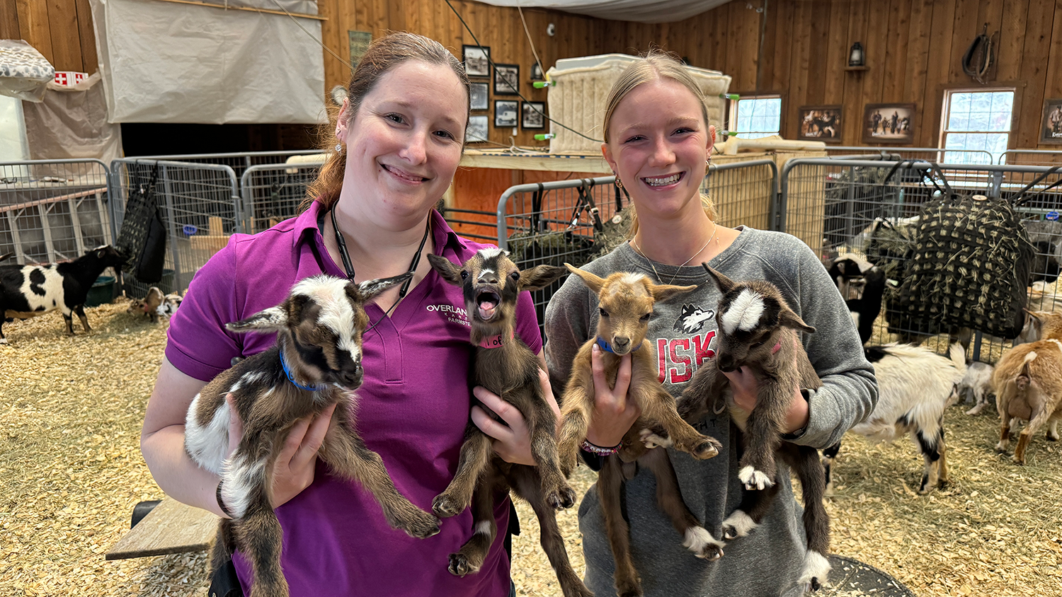 Two Deanna Rose Children's Farmstead staff members pose for a photo with baby goats.