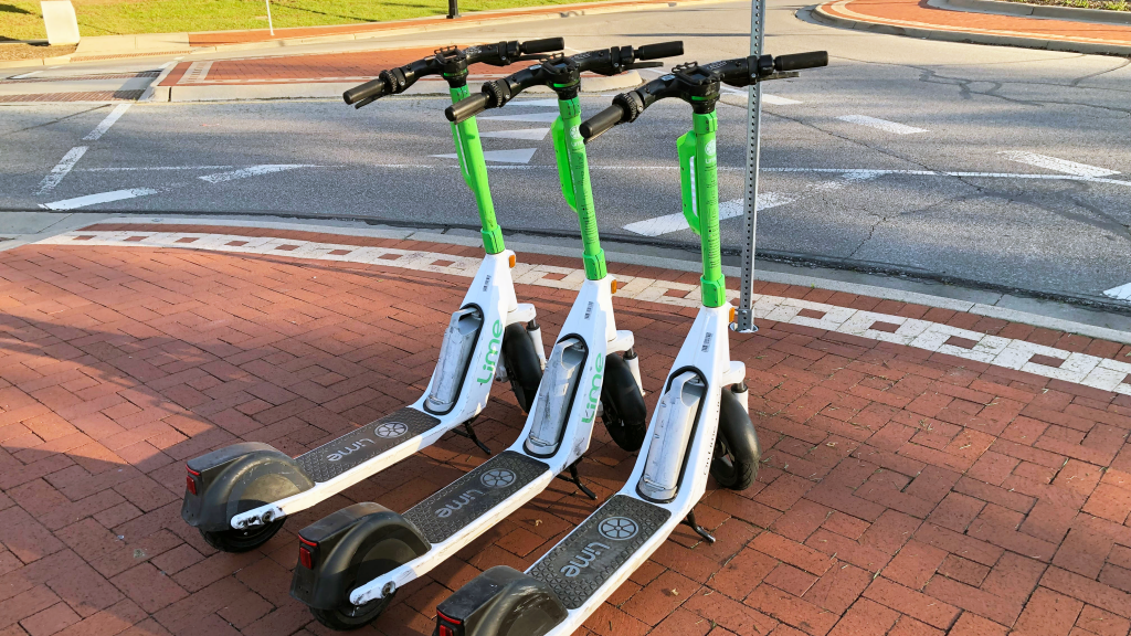 Three Lime e-scooters parked near the sidewalk.