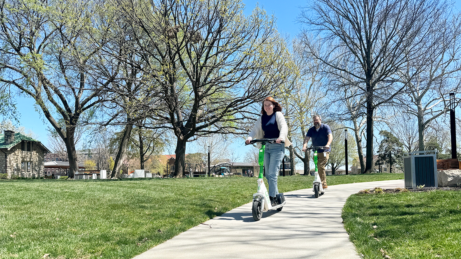 Two people riding Lime e-scooters through Thompson Park.