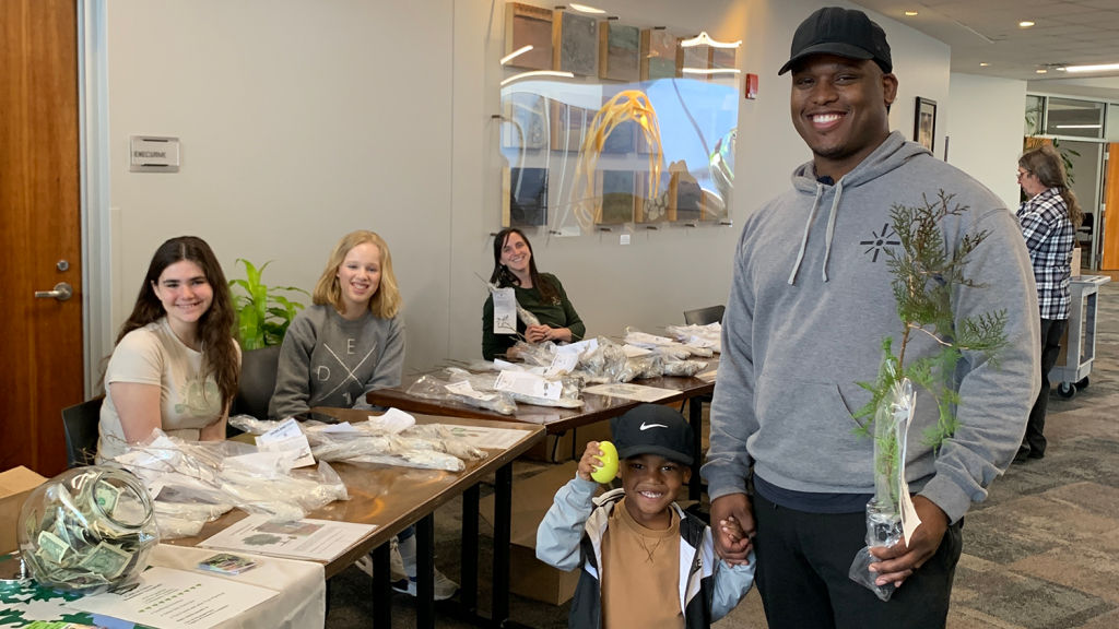 A resident and his young child pose with a seedling they received at the 2023 Arbor Day Seedling Giveaway.