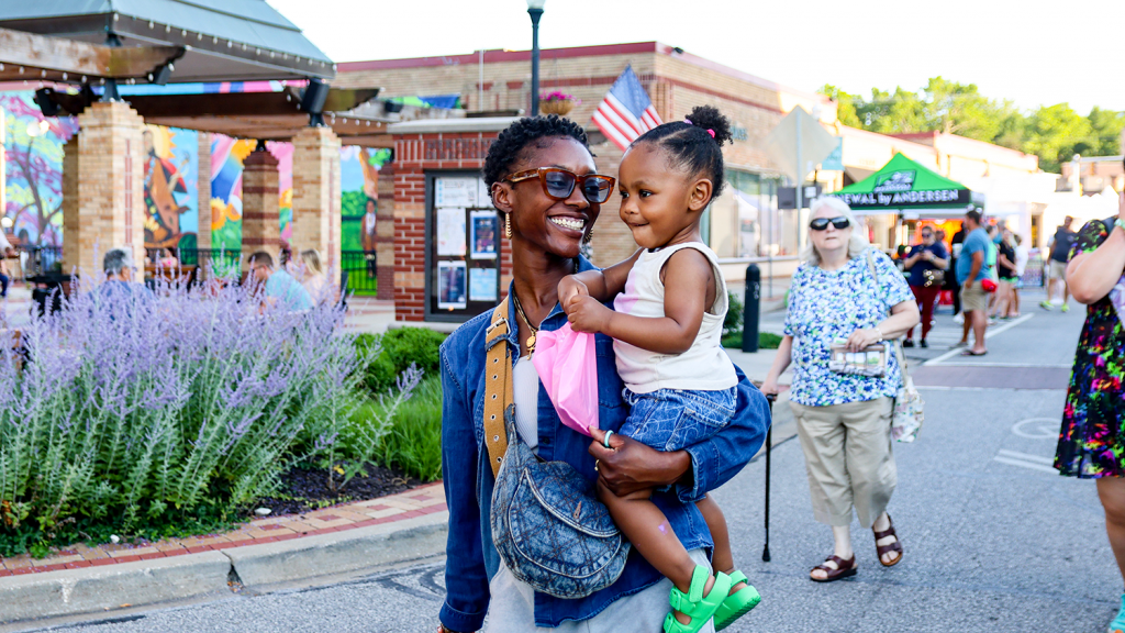 A resident carries her young daughter as they walk through Downtown Overland Park.