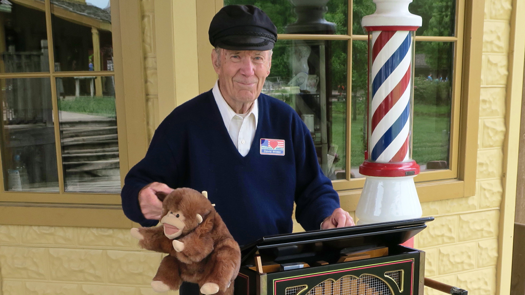 A smiling man operates an old music box.