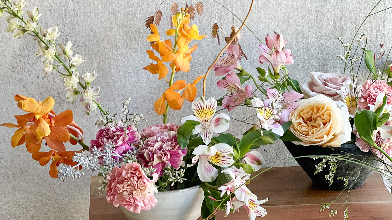 Two small pots hold blooming white, orange and pink flowers.