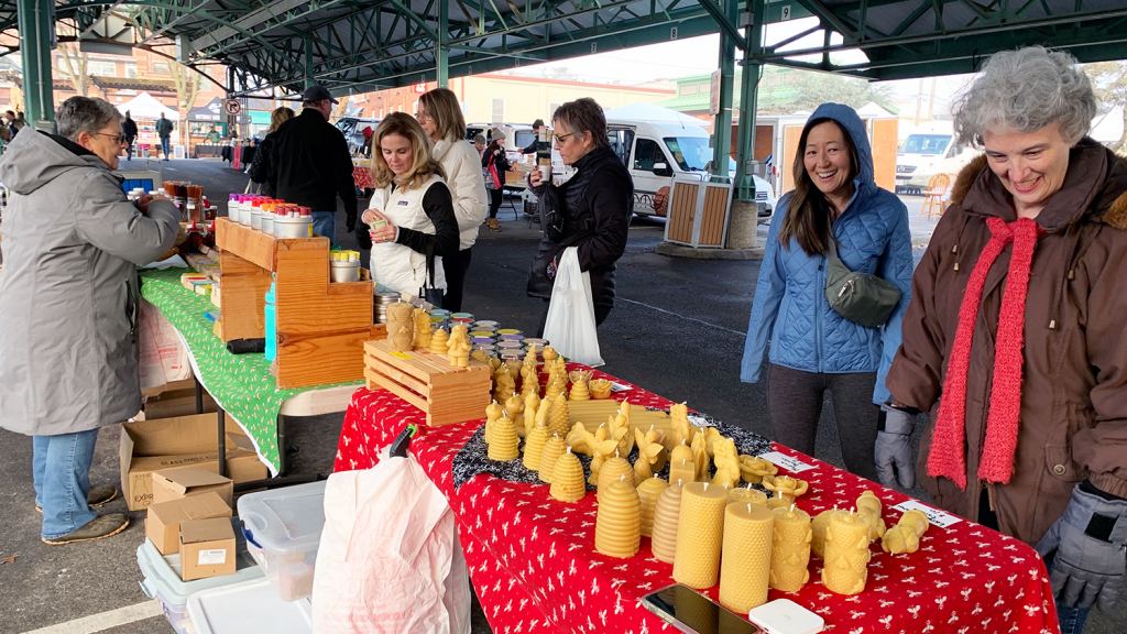 Shoppers browse from hand-made candles at the Holiday Market at the Overland Park Farmers' Market.