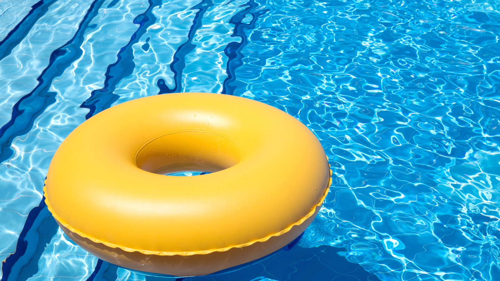 A yellow inner tube floats in a bright blue pool.