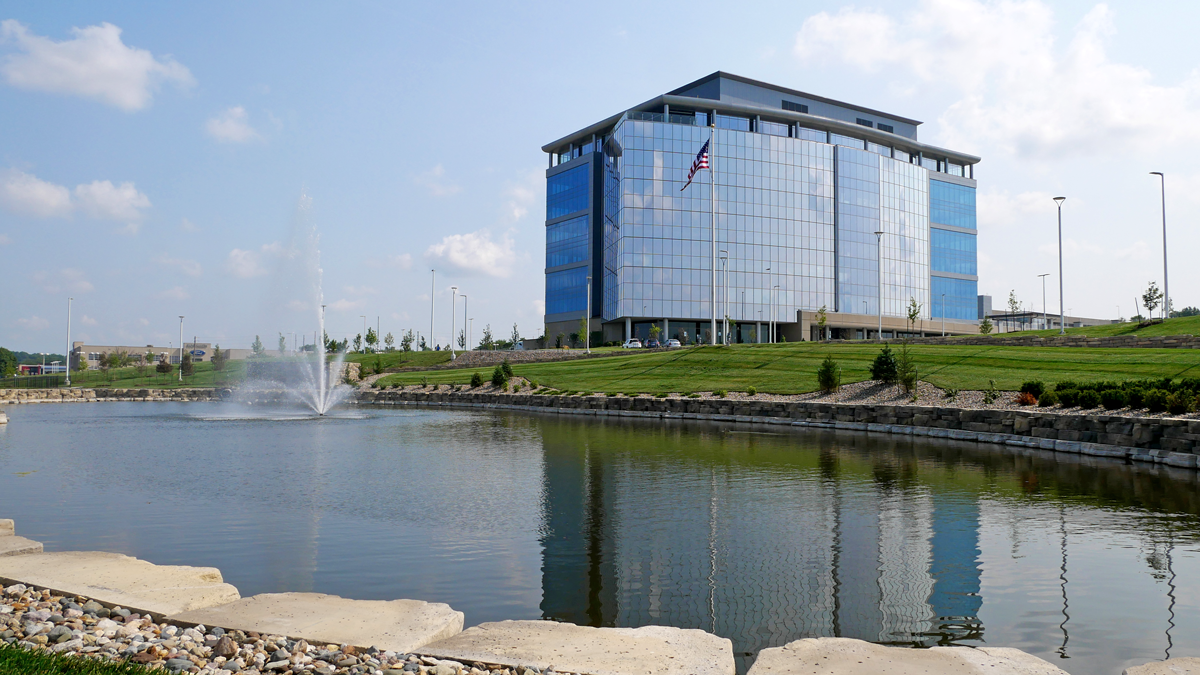 A large pond with a running fountain sits in front of the blue glass Shamrock building.