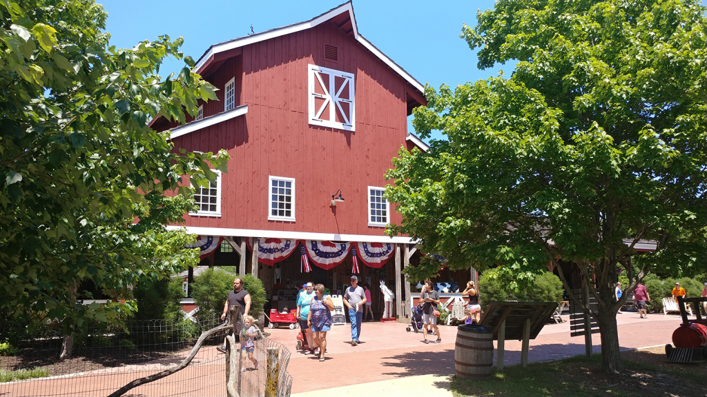 People walk in front of the red farmstead building at Deanna Rose Children's Farmstead.