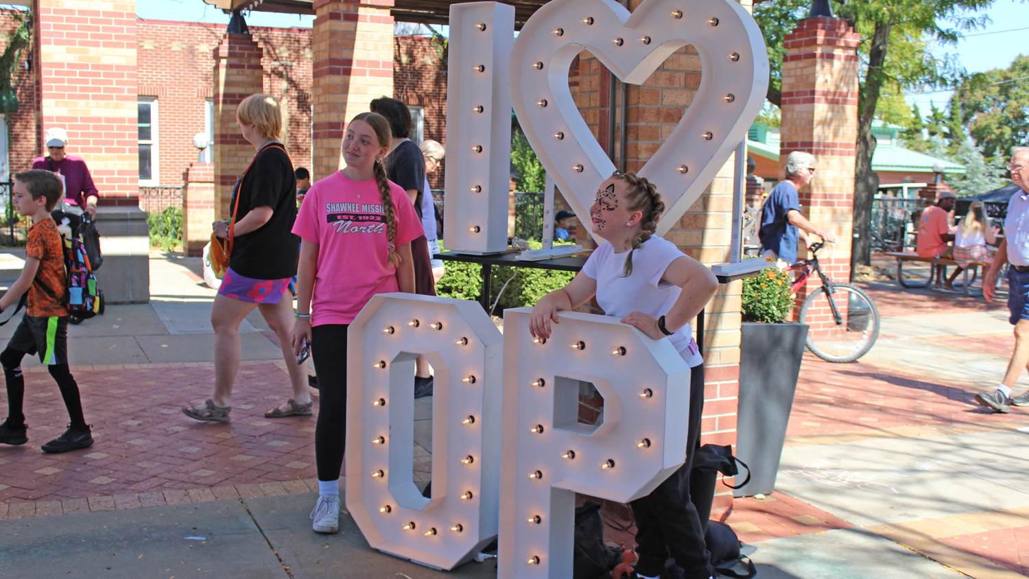Two girls stand for a photo with large, white letters that say "I Love OP."