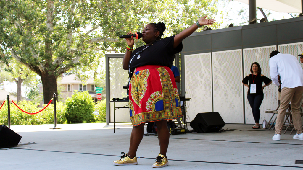 Woman sings expressively into a microphone on stage at Juneteenth Peace March and Rally.