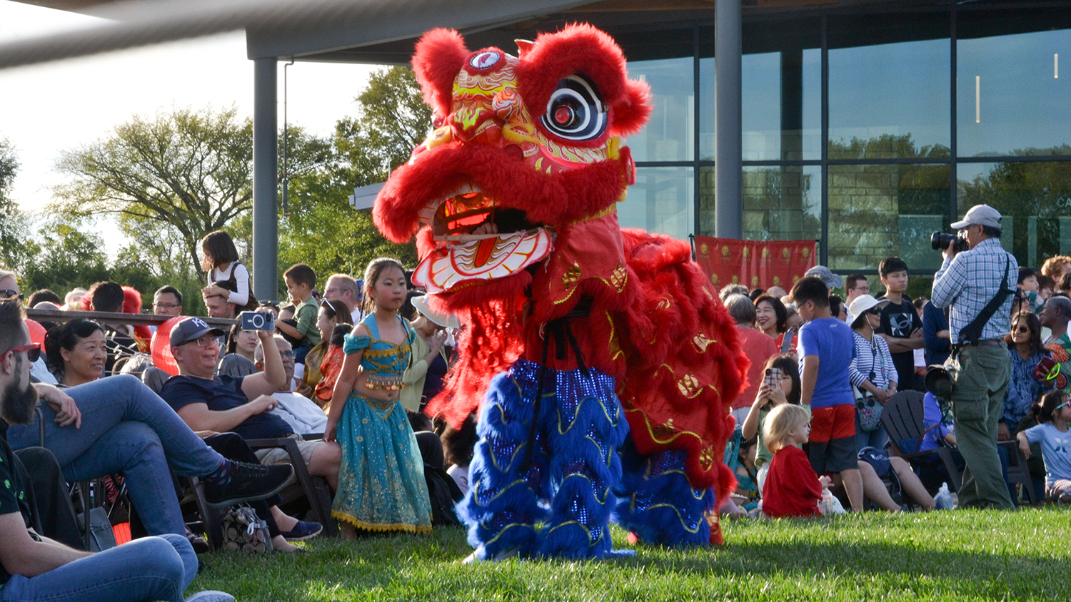Two performers stand in a red and blue Chinese dragon costume in front of a crowd.