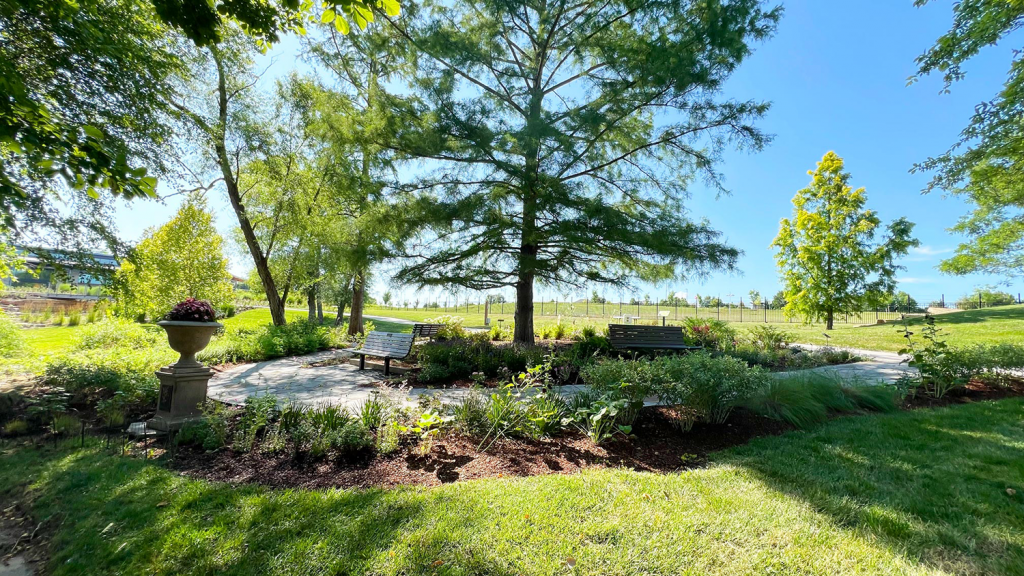 The Emily Dickinson Garden at the Overland Park Arboretum & Botanical Gardens, including a stone pathway, three wooden benches and various plants and trees.